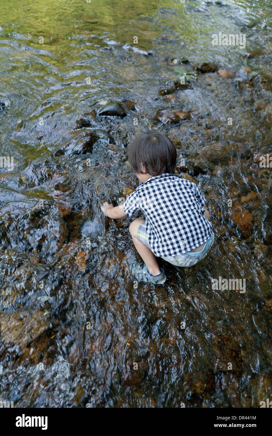 Asian boy playing in stream - USA Banque D'Images