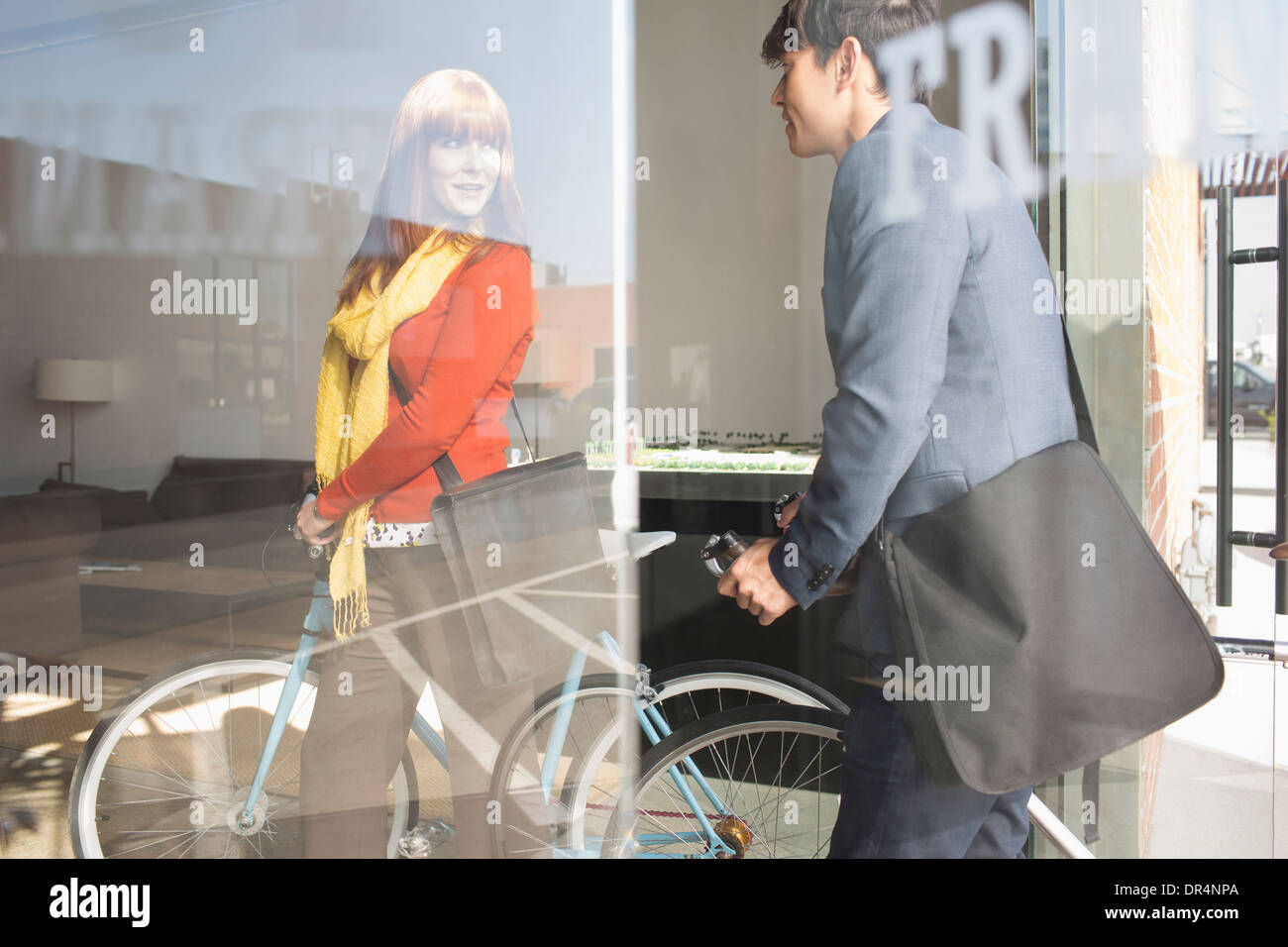 Les gens d'affaires wheeling bicyclettes dans office Banque D'Images