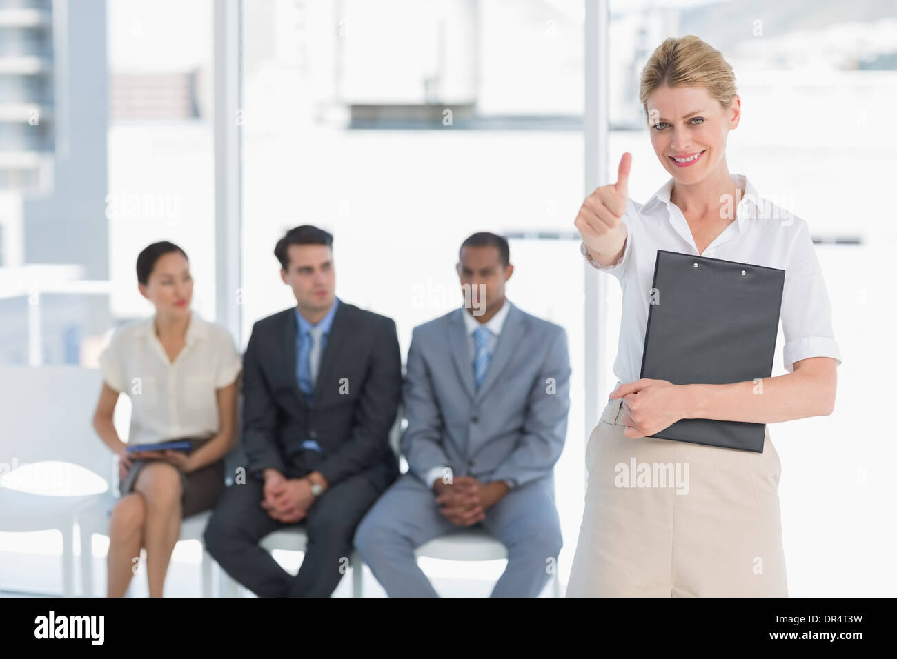 Woman gesturing Thumbs up avec des personnes en attente d'interview in office Banque D'Images