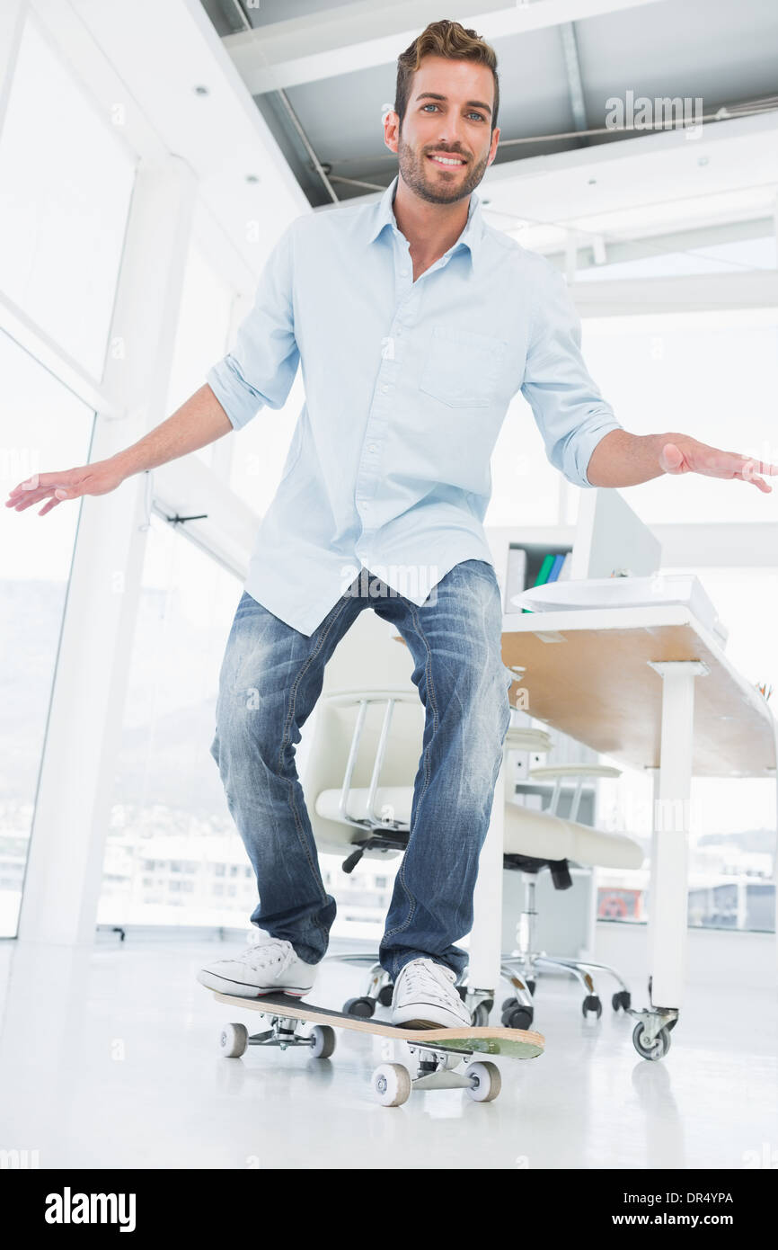 Toute la longueur d'un jeune homme skateboarding in office Banque D'Images