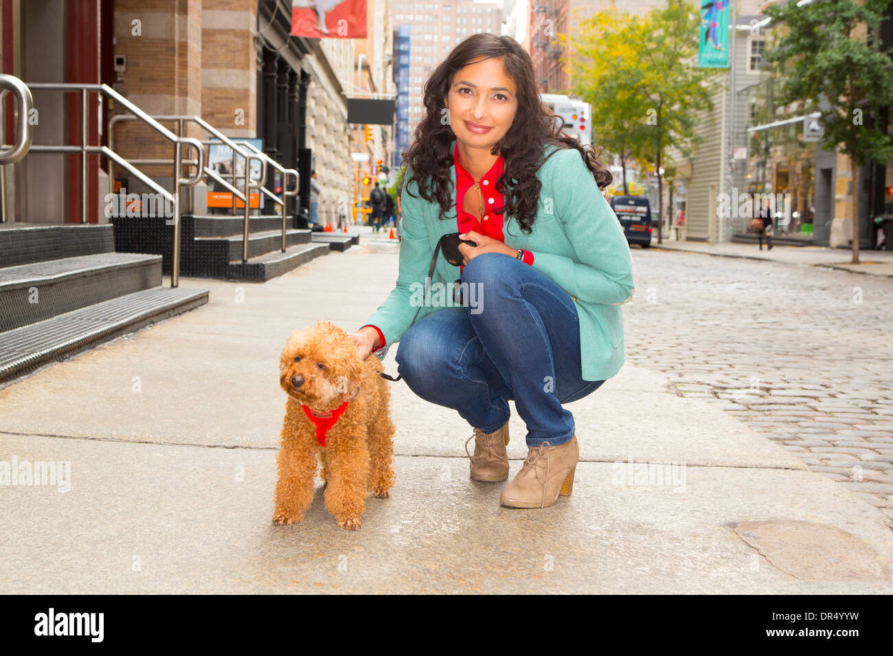 Mixed Race woman walking dog sur trottoir urbain Banque D'Images