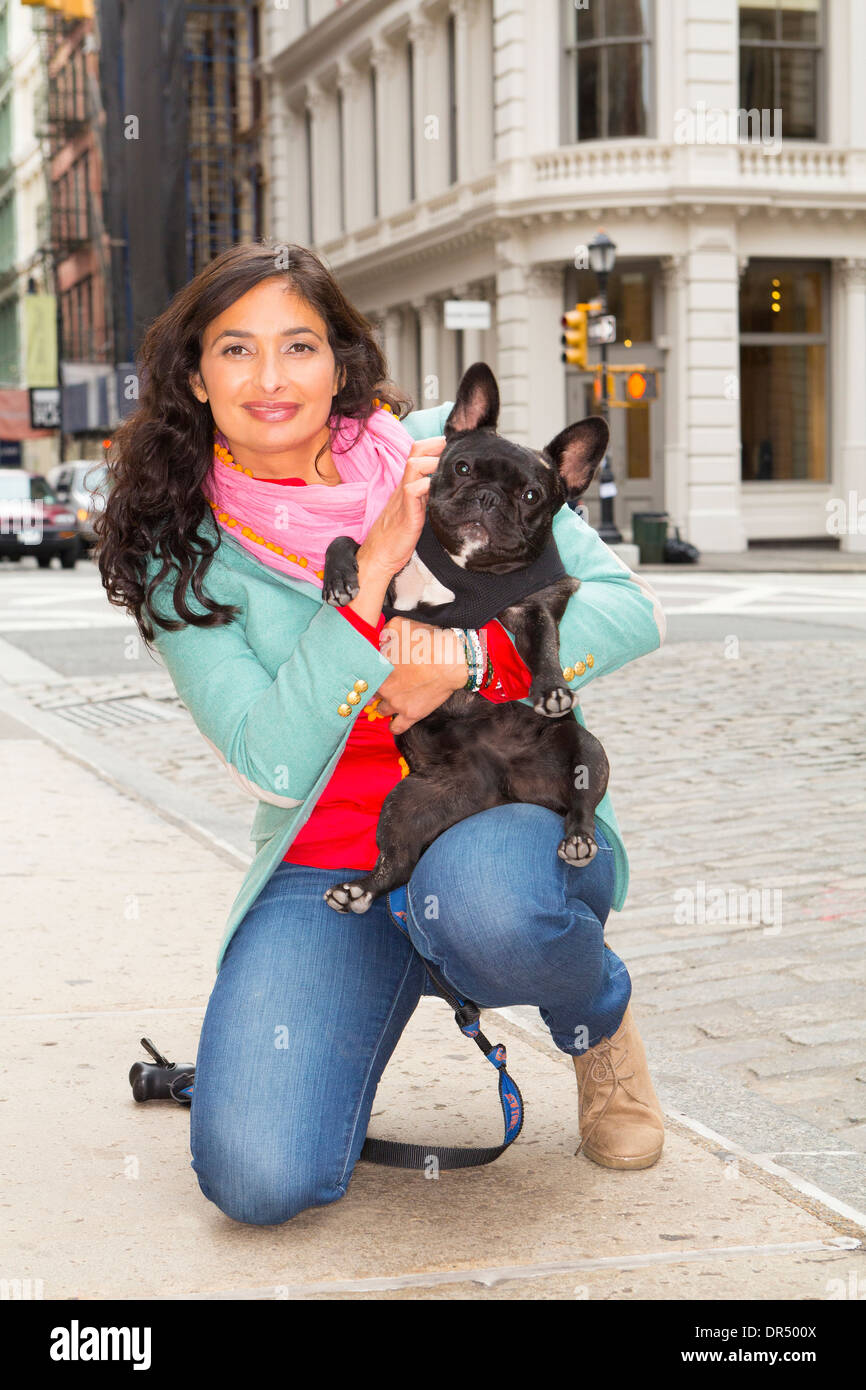 Mixed Race woman holding dog sur trottoir urbain Banque D'Images