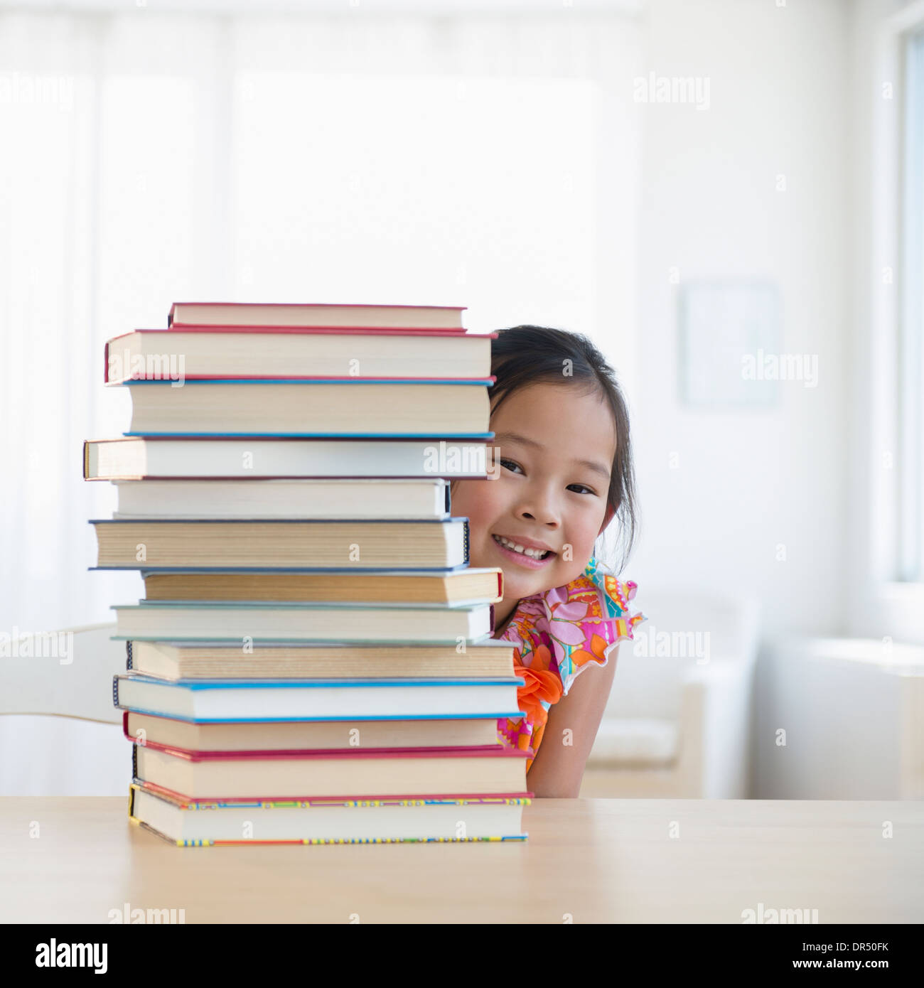 Fille coréenne peeking de derrière la pile de livres Banque D'Images