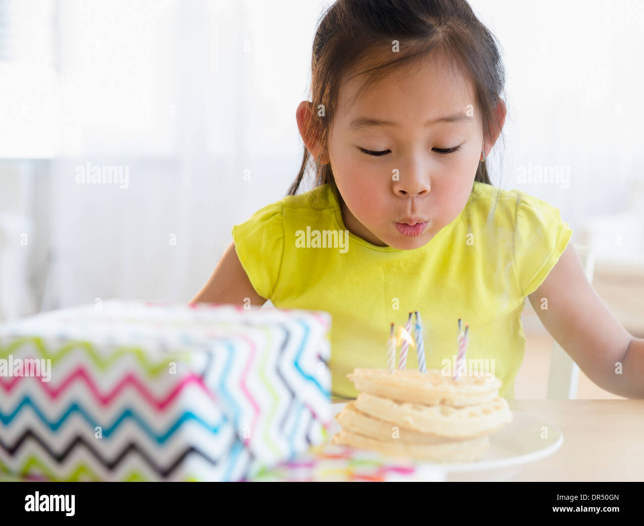 Korean girl blowing out candles on cake Banque D'Images