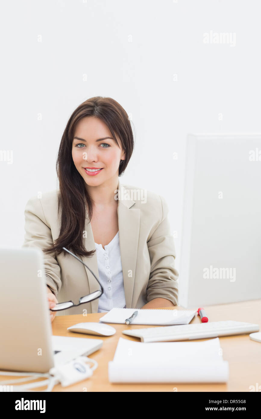 Bien habillé woman with laptop at desk in office Banque D'Images