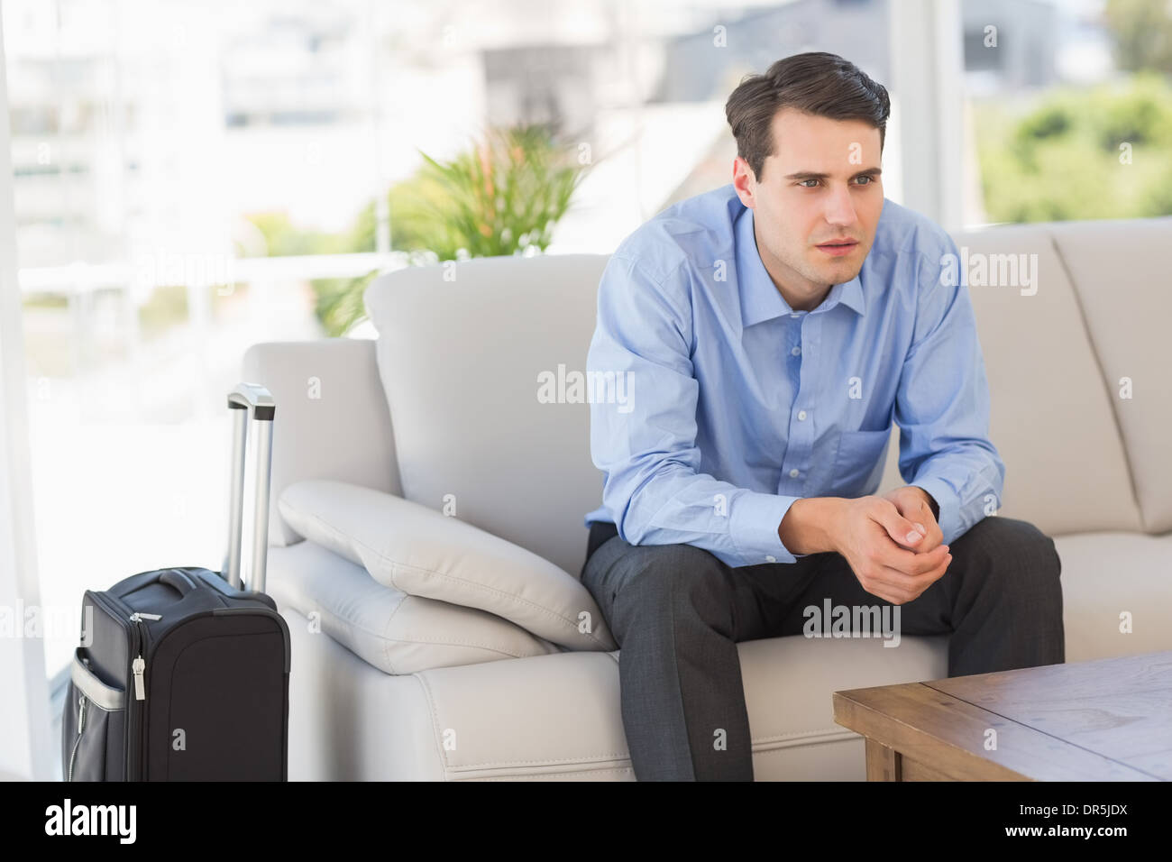 Businessman sitting on couch en attente de partir en voyage d'affaires Banque D'Images