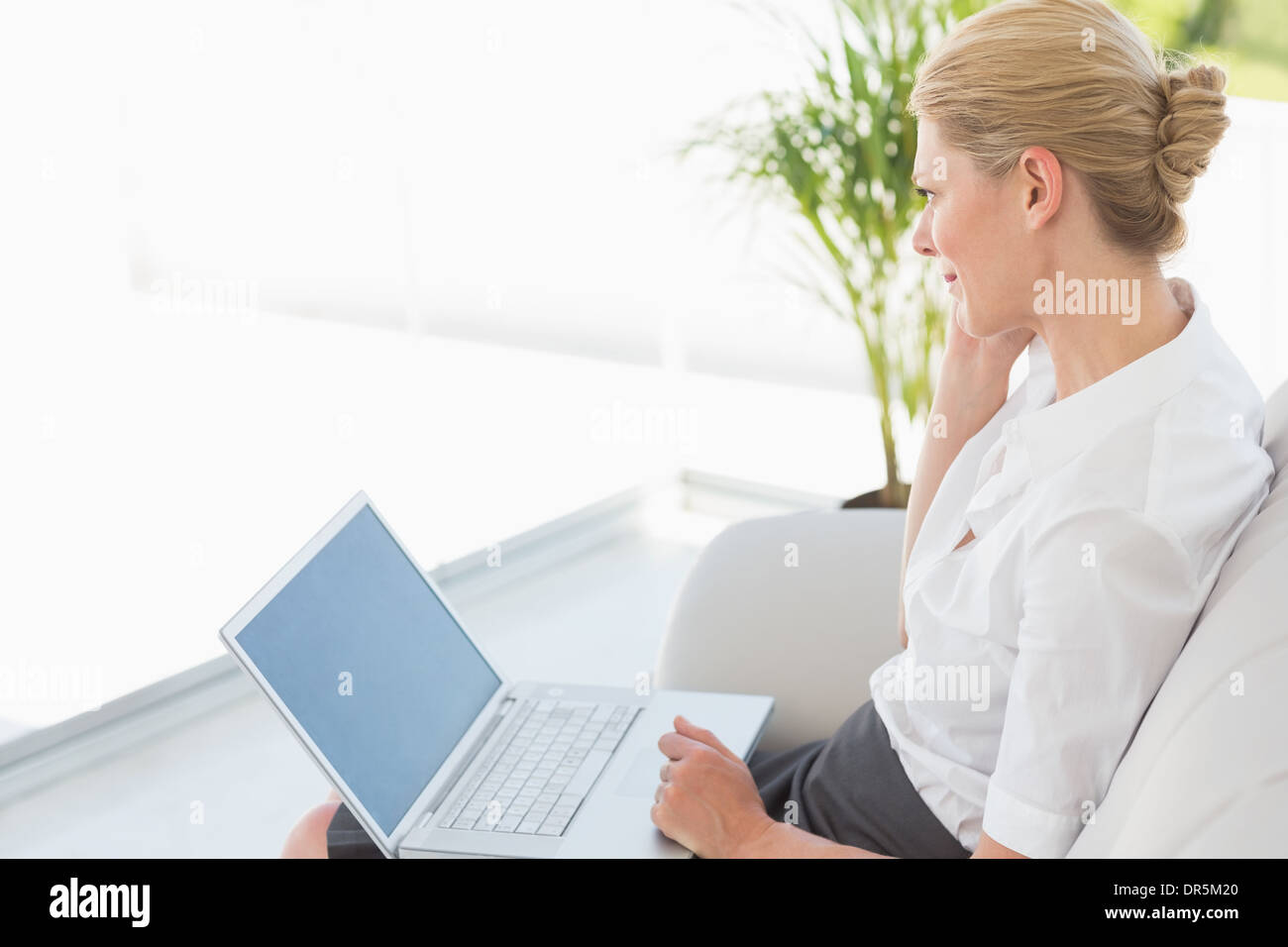 Businesswoman sitting on the couch working on laptop Banque D'Images