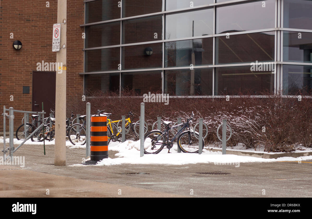 Les vélos dans un support à bicyclettes dans la neige en hiver à l'université. Banque D'Images