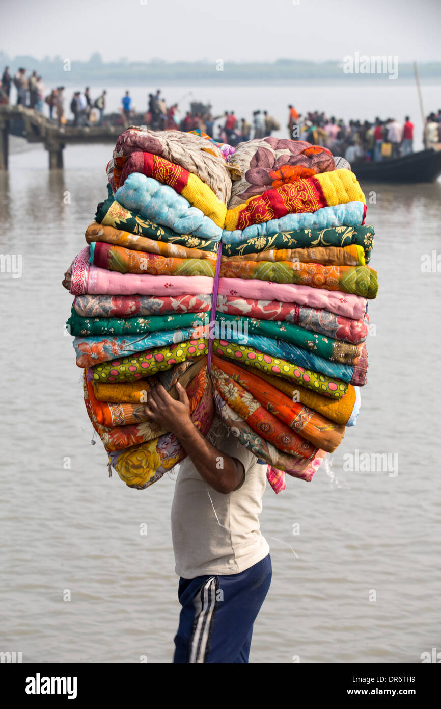 Un homme portant des tissus dans les Sunderbans, une zone de basse altitude du delta du Gange dans l'Est de l'Inde, qui est très vulnérable à la mer Banque D'Images