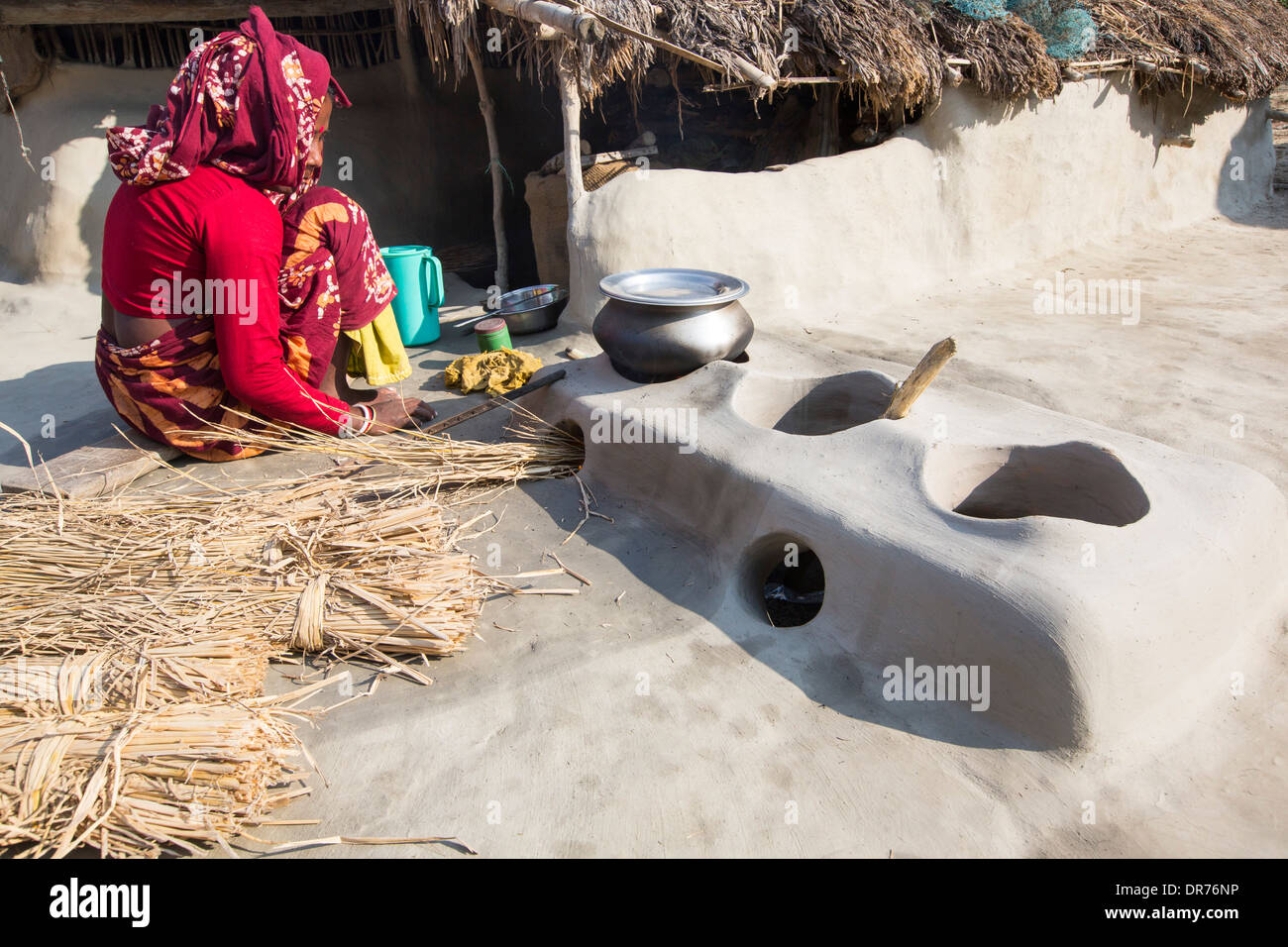 Une femme agriculteur de subsistance la cuisson sur un four en argile traditionnel, à l'aide de tiges de riz comme biocarburant dans les Sunderbans, Ganges, Delta, de l'Inde. La région est très faible élévation et vulnérables à la montée du niveau de la mer. Toutes les parties de la récolte de riz sont utilisés, et la vie des villageois est très autonome, avec une petite empreinte carbone. Banque D'Images
