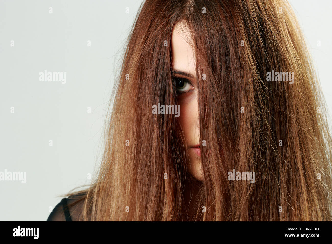 Closeup portrait of a young woman face couverte de cheveux Banque D'Images