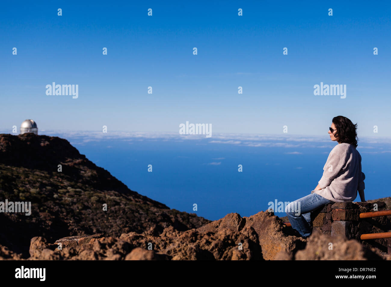 Jolie fille assise près de télescopes à la Roque de los Muchachos astrophysique Observatoire sur La Palma, Îles Canaries, Espagne. Banque D'Images