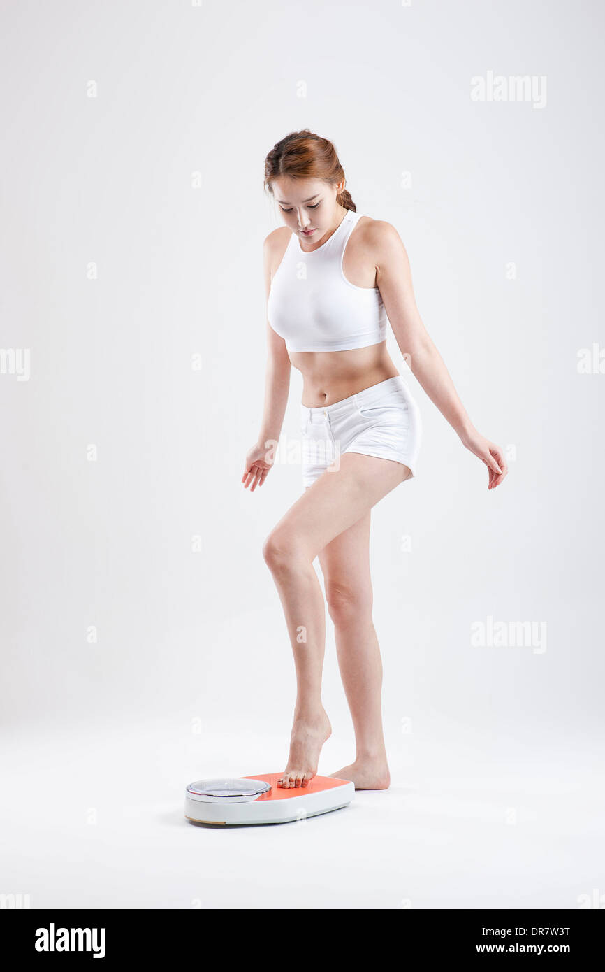 Une femme se mesure sur l'échelle de pesage Banque D'Images