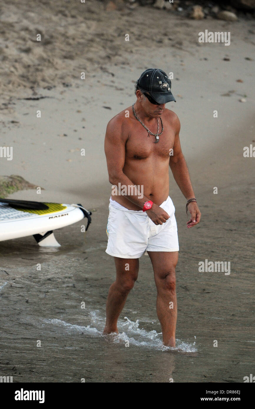 Le chanteur Bruce Springsteen faisant paddlesurf sur une plage en vacances à Majorque en 2013. Banque D'Images