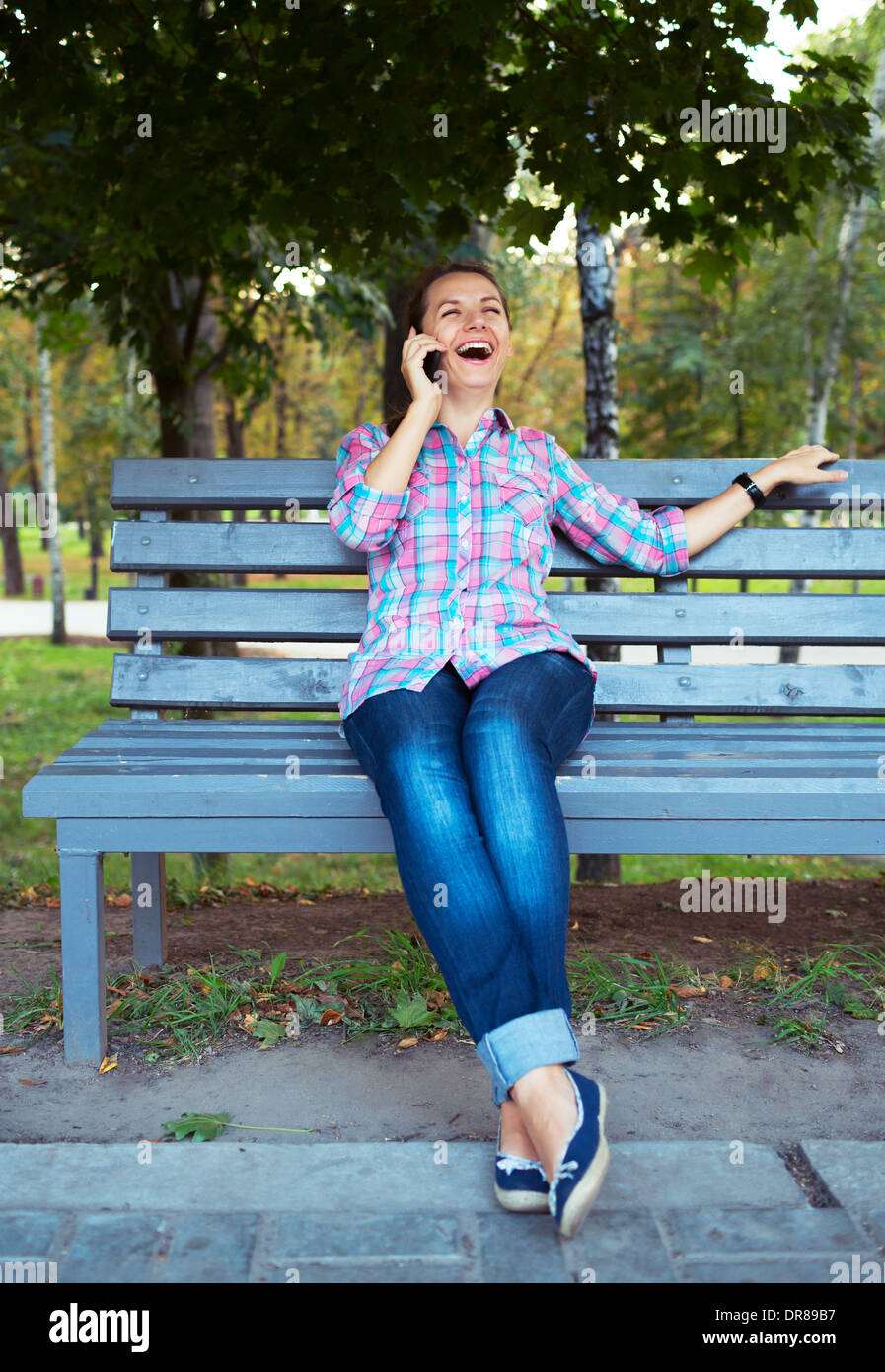 Un portrait d'une jeune femme dans un parc sur le banc à parler au téléphone Banque D'Images