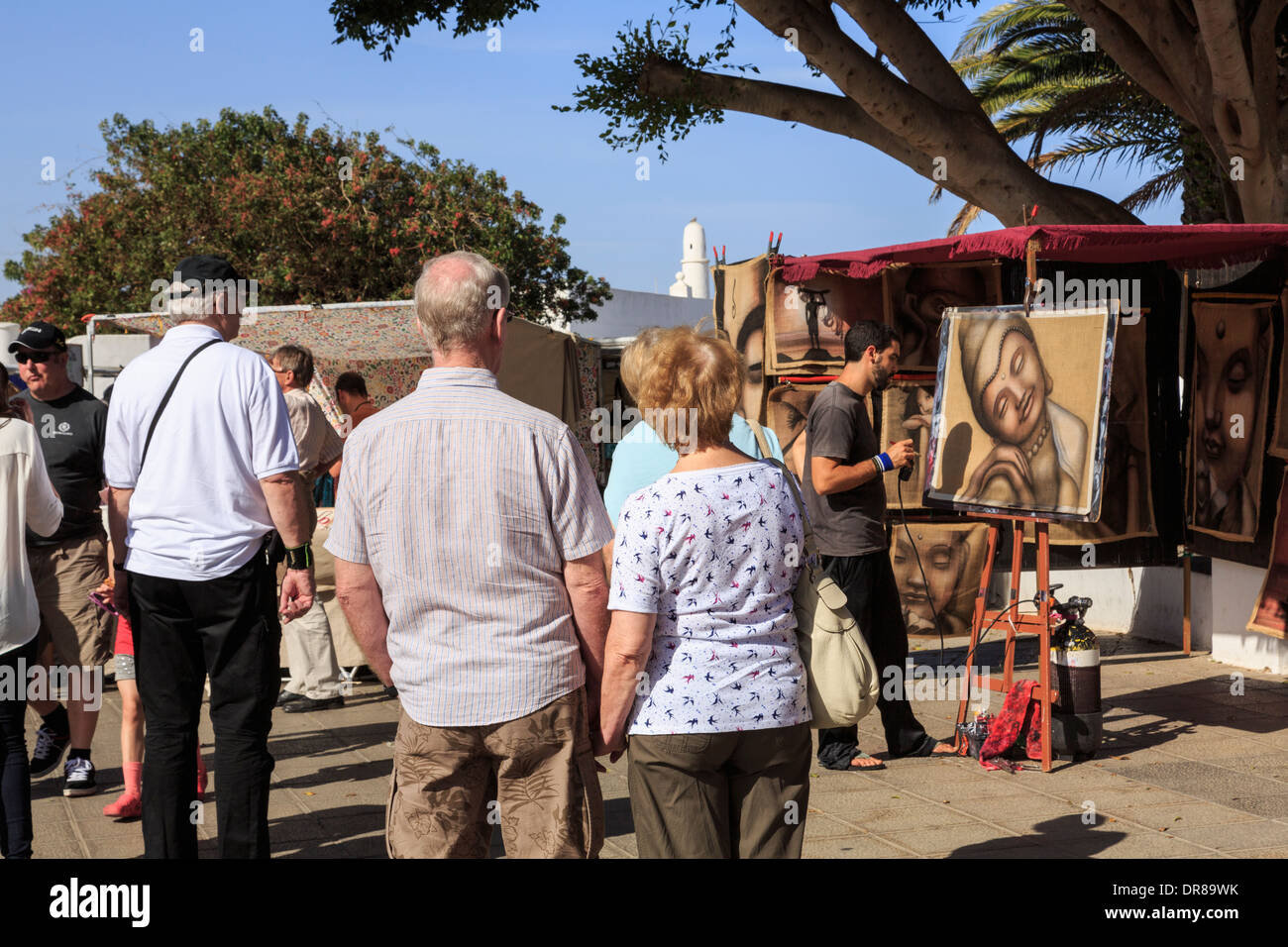 Les touristes à regarder un artiste au travail peinture photos dans l'état occupé dimanche street market dans Teguise, Lanzarote, îles Canaries, Espagne Banque D'Images