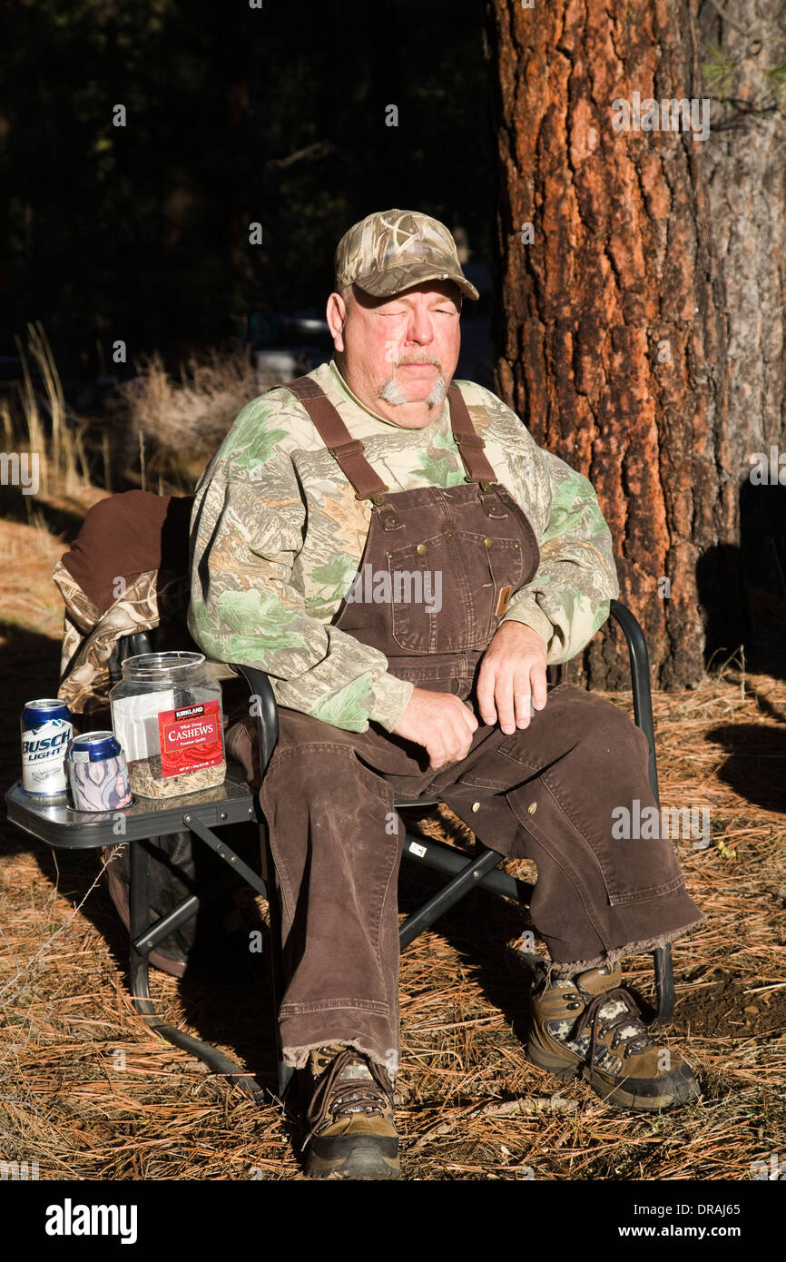Un homme âgé habillé en salopette est assis sur une chaise près du camp Metolius, Oregon Banque D'Images