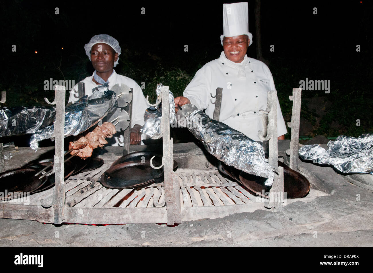 Otjibamba Lodge chef et faire cuire la viande à rôtir avec barbecue extérieur en soirée le Parc national Amboseli Kenya Afrique de l'Est Banque D'Images