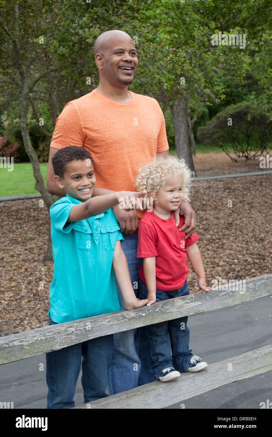 Heureux père avec enfants à la recherche à vue depuis une clôture en bois Banque D'Images