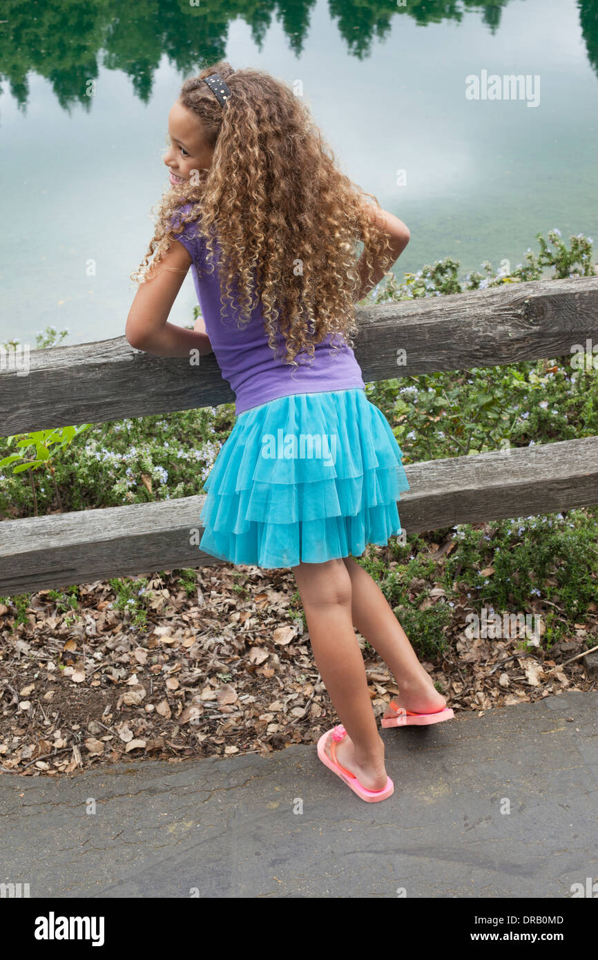 Vue arrière d'une jeune fille appuyée sur une clôture en face de river Banque D'Images