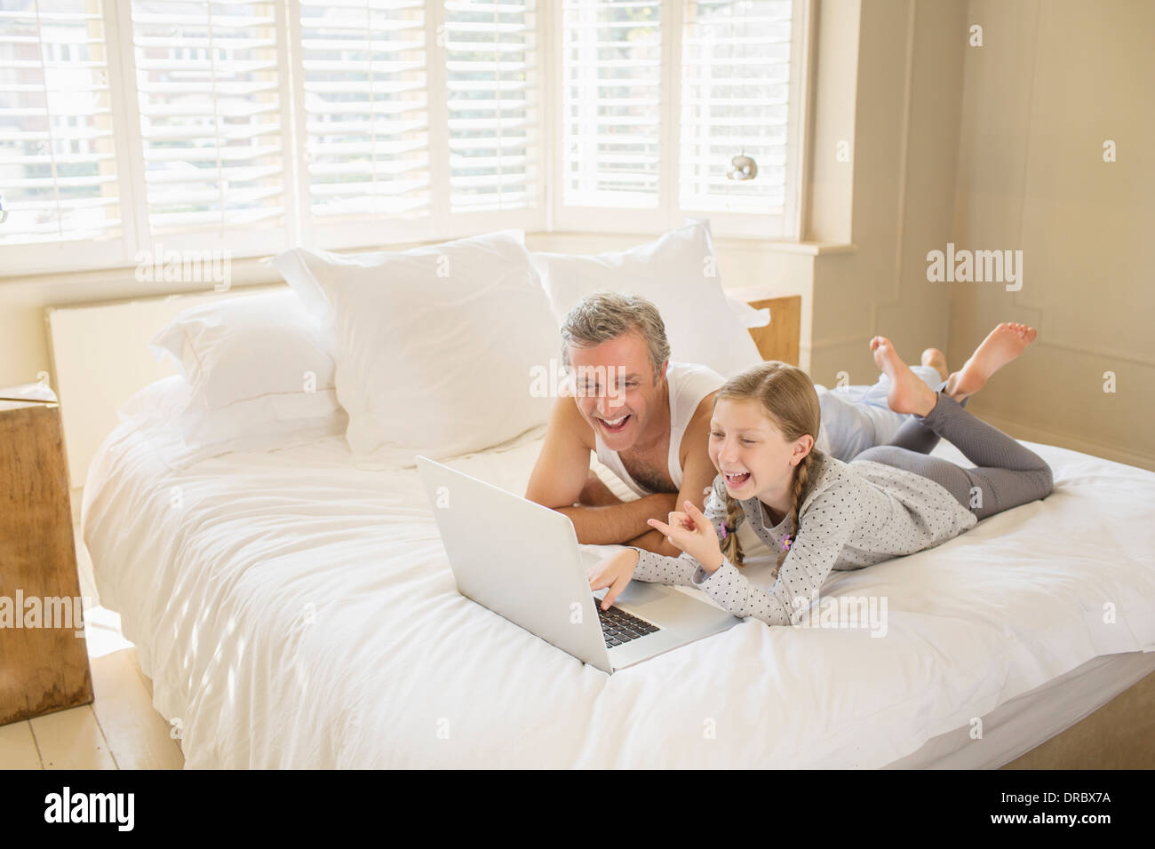 Père et fille using laptop on bed Banque D'Images