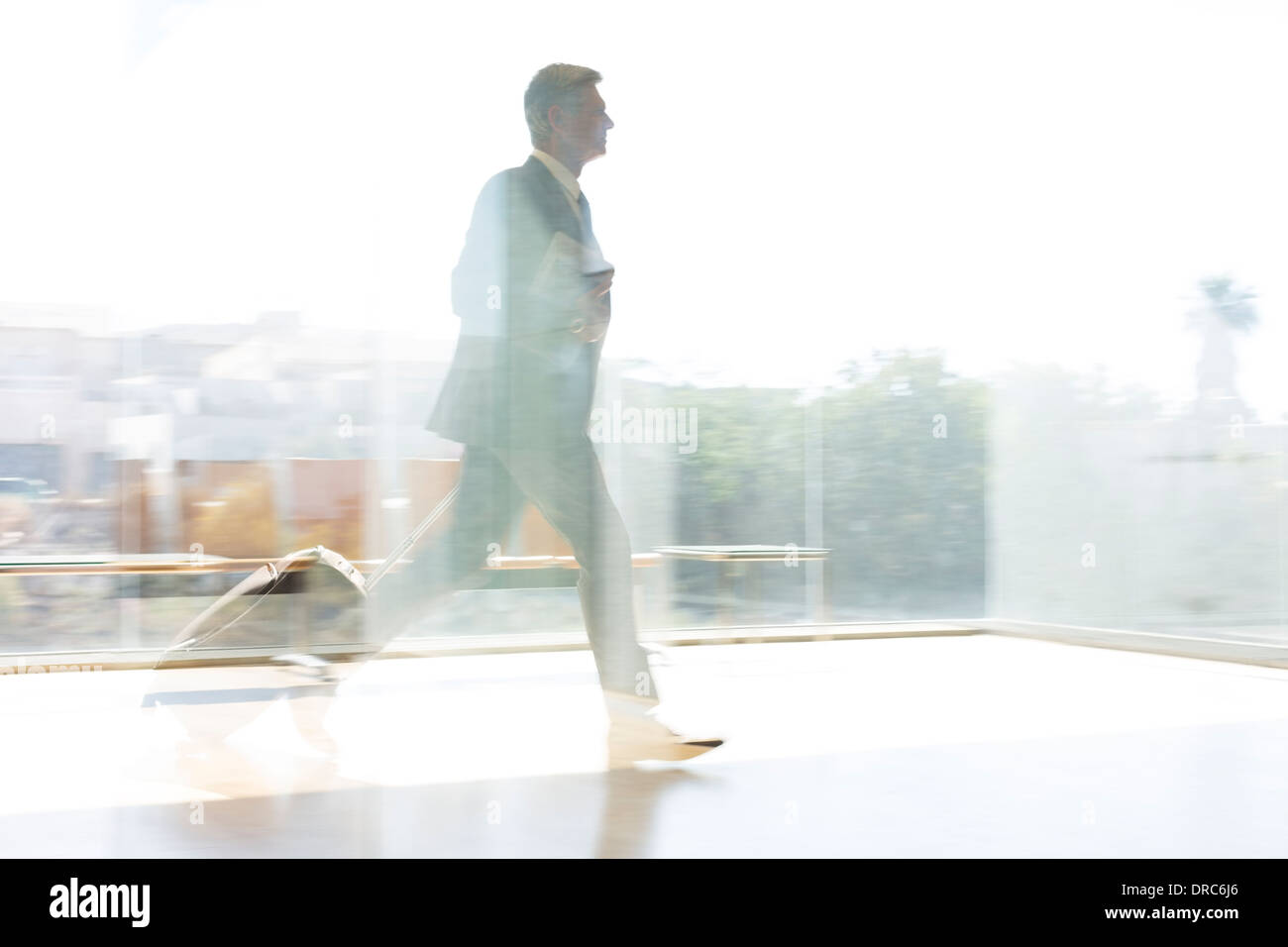 Businessman running in sunny airport Banque D'Images