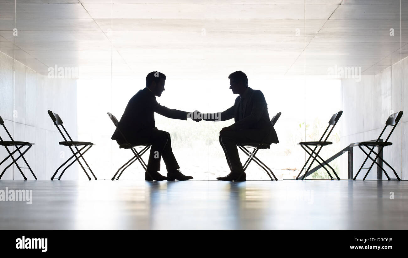 Businessmen shaking hands in office Banque D'Images