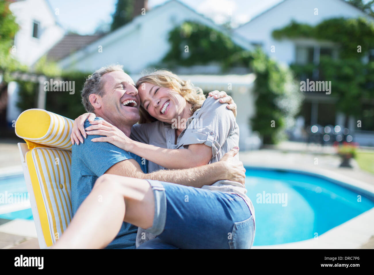 Couple relaxing in lounge chair at poolside Banque D'Images