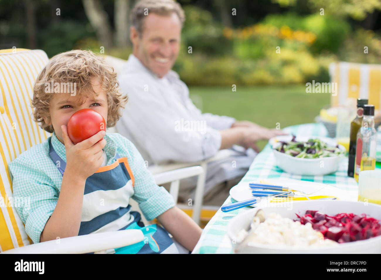 Garçon jouant avec de la nourriture à table in backyard Banque D'Images