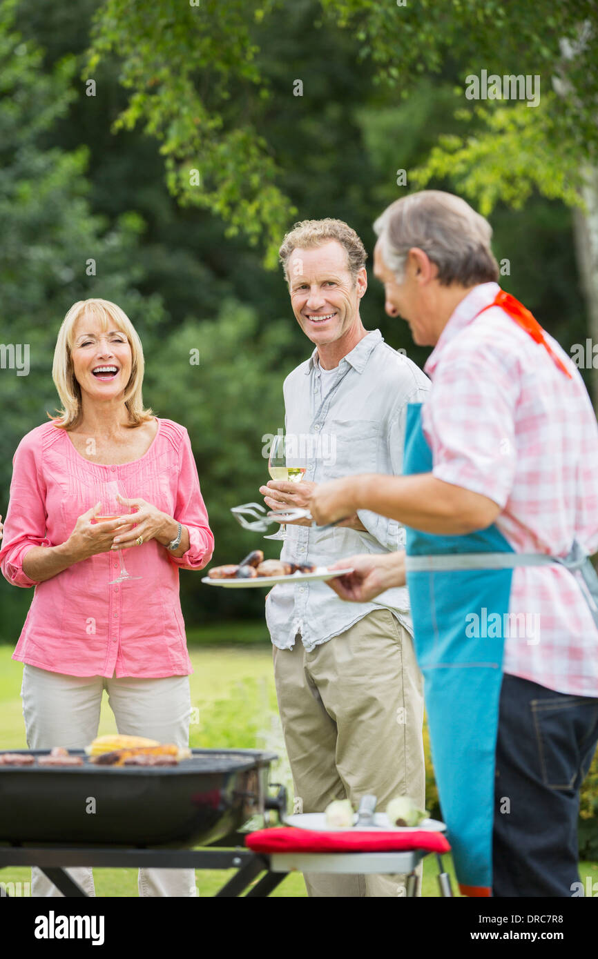 Family standing at barbecue in backyard Banque D'Images