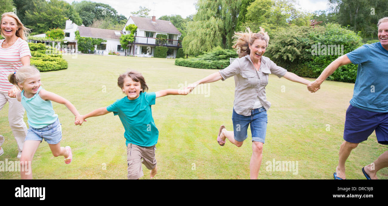 Multi-generation family holding hands and running in backyard Banque D'Images
