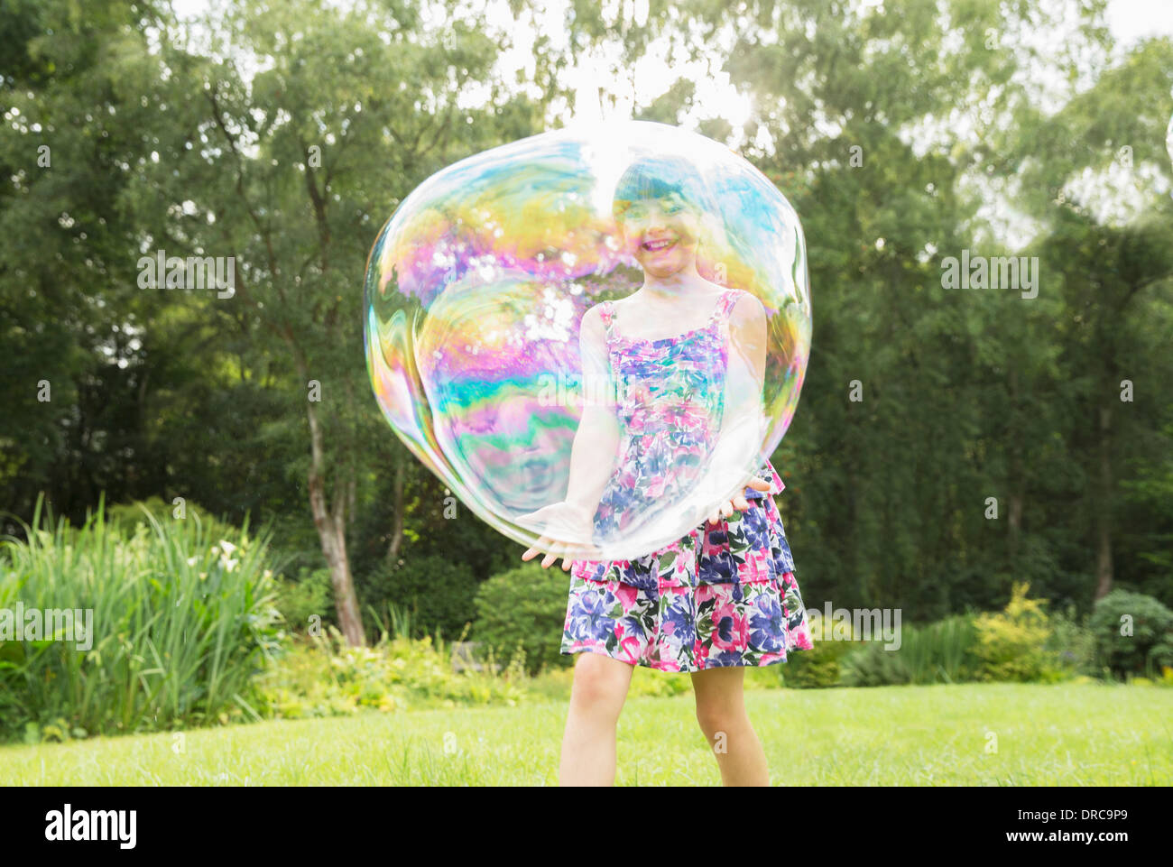 Père et fille jouer avec des grosses bulles dans la cour Banque D'Images