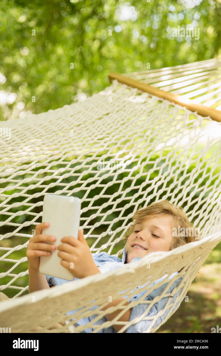 Boy using digital tablet in hammock Banque D'Images