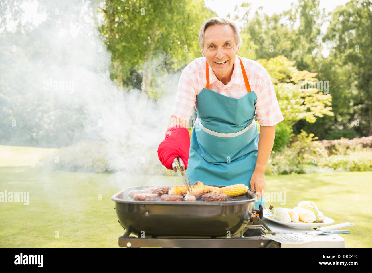 Man grilling food sur barbecue in backyard Banque D'Images