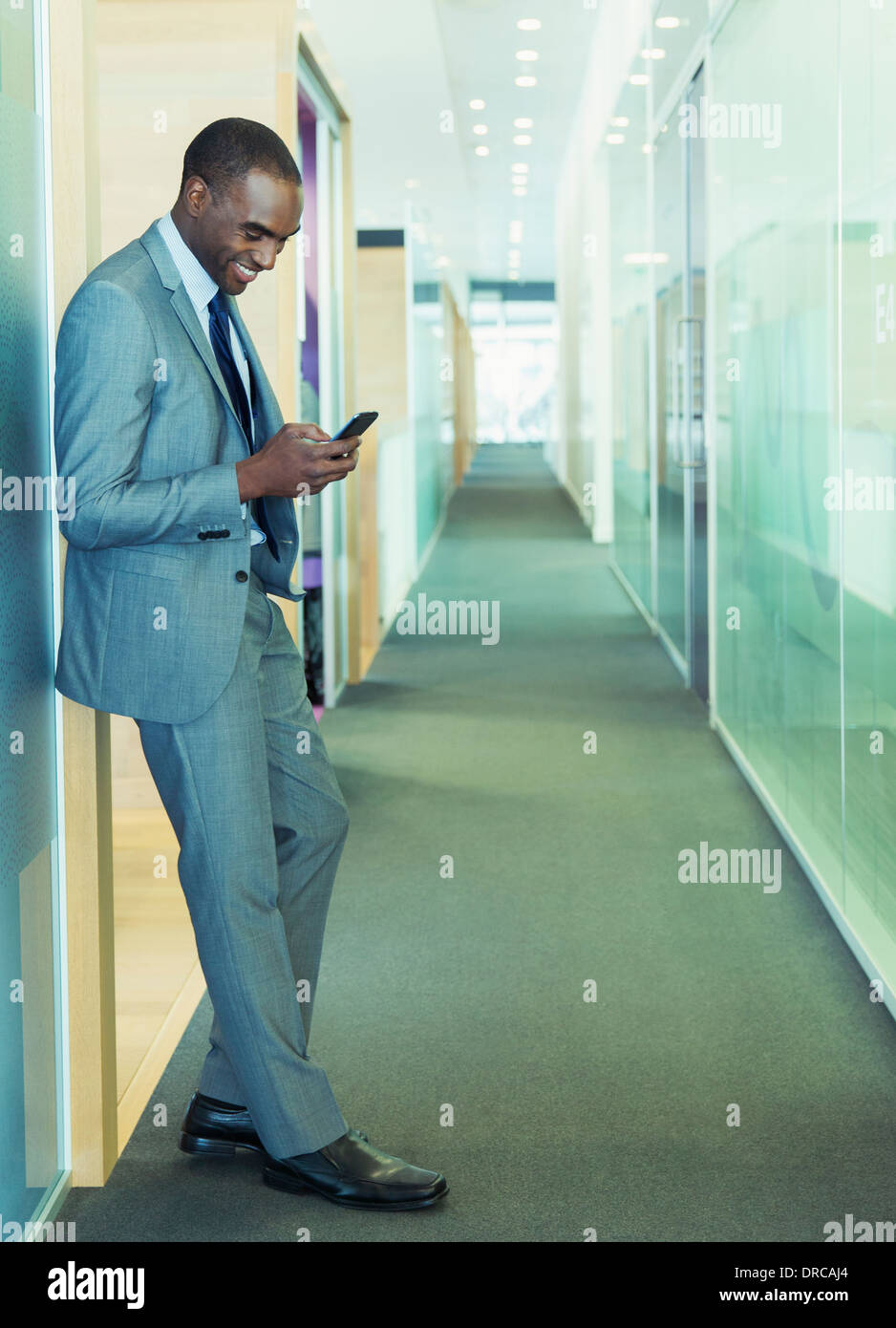 Businessman using cell phone in office corridor Banque D'Images
