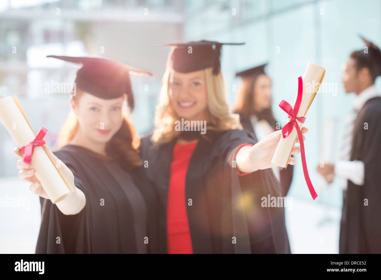 Les diplômés Smiling holding diplomas Banque D'Images