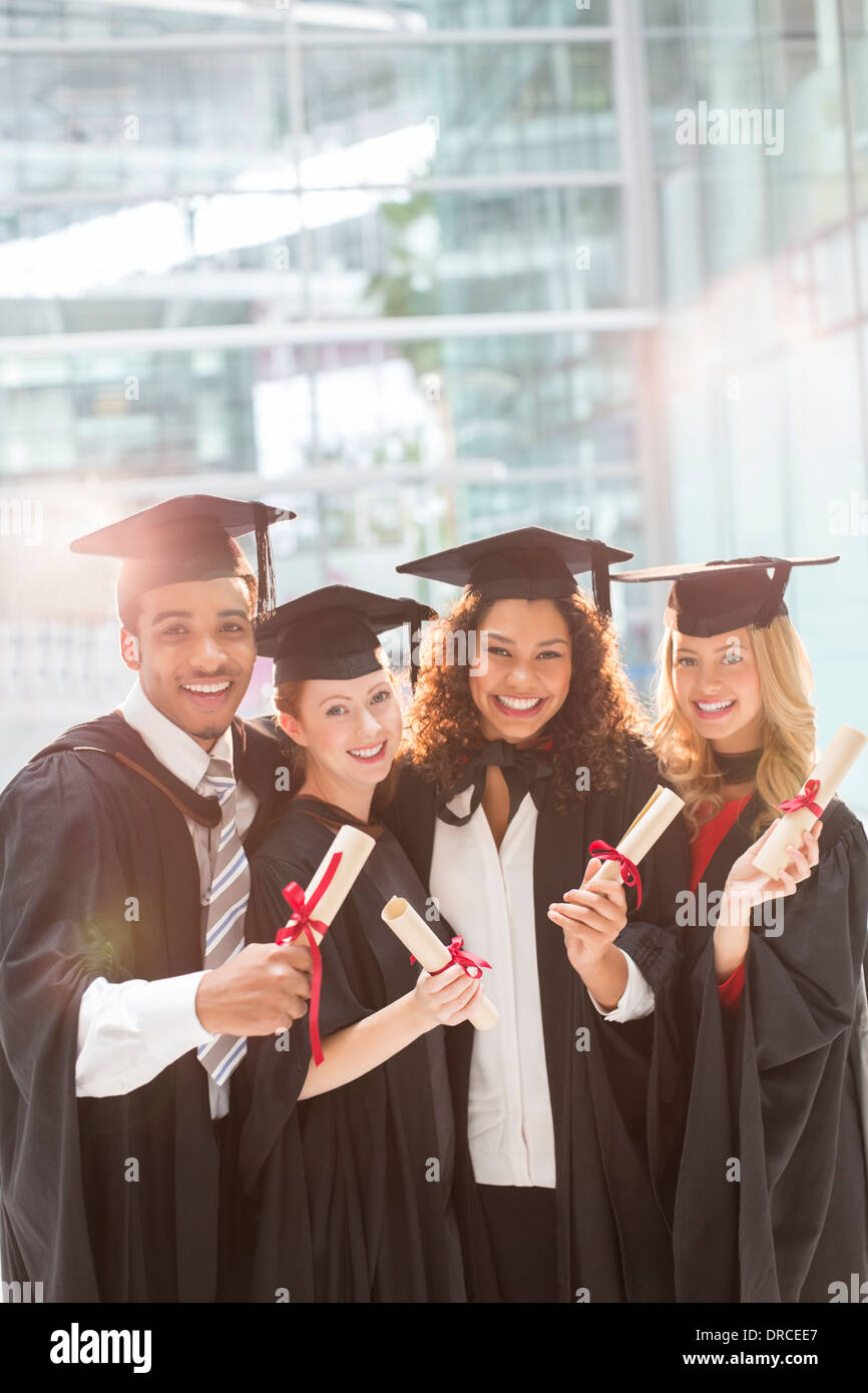Les diplômés Smiling holding diplomas Banque D'Images