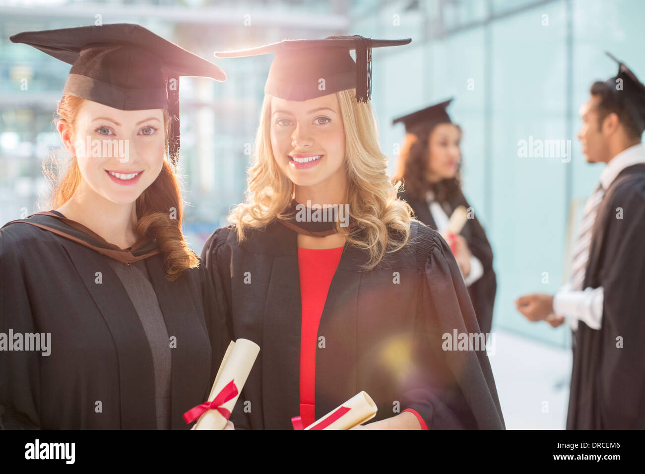 Les diplômés Smiling holding diplomas Banque D'Images