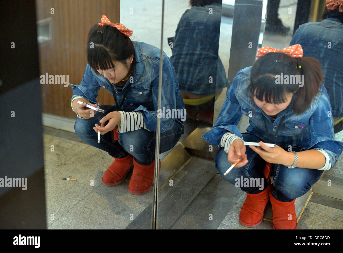 Une femme vérifie téléphone mobile tout en fumant à Beijing, Chine. Banque D'Images