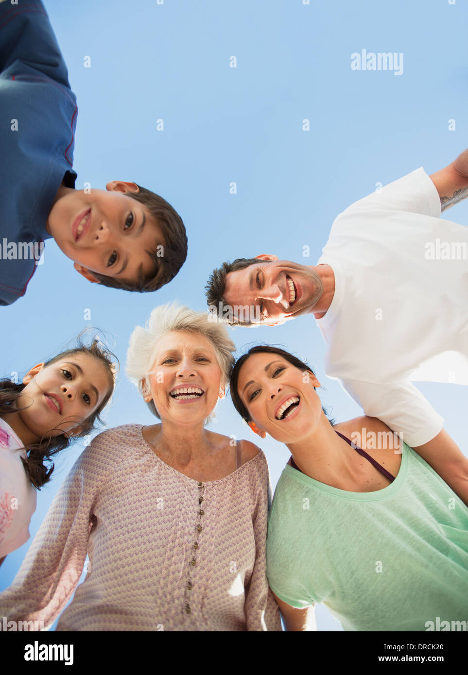 Multi-generation family smiling in huddle contre le ciel bleu Banque D'Images