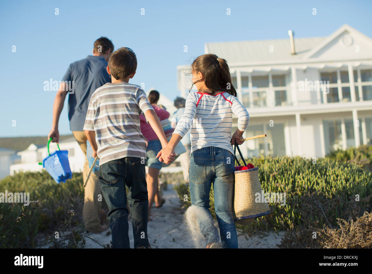 Brother and sister holding hands on beach path Banque D'Images