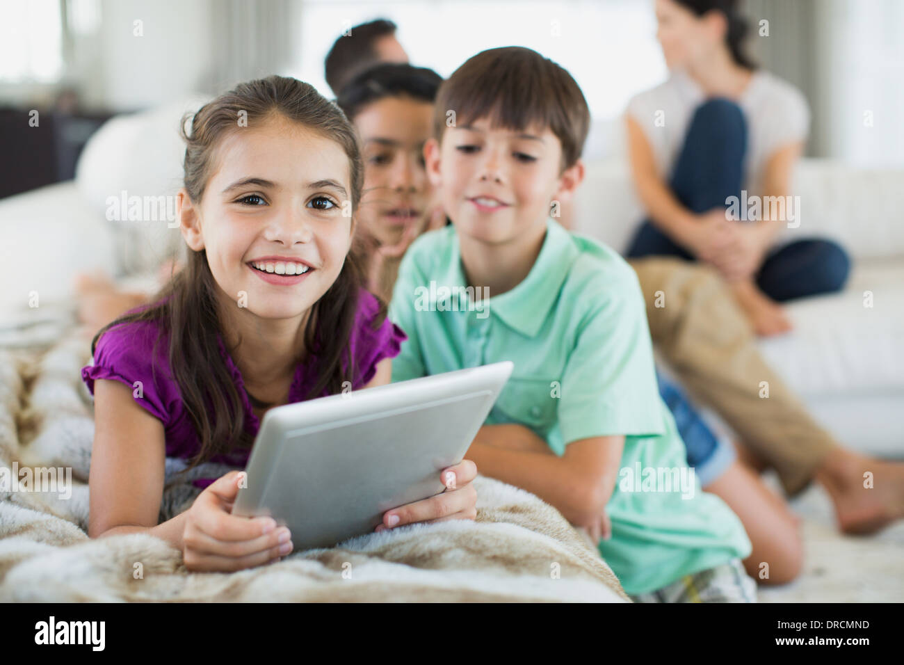 Enfants using digital tablet on sofa in living room Banque D'Images