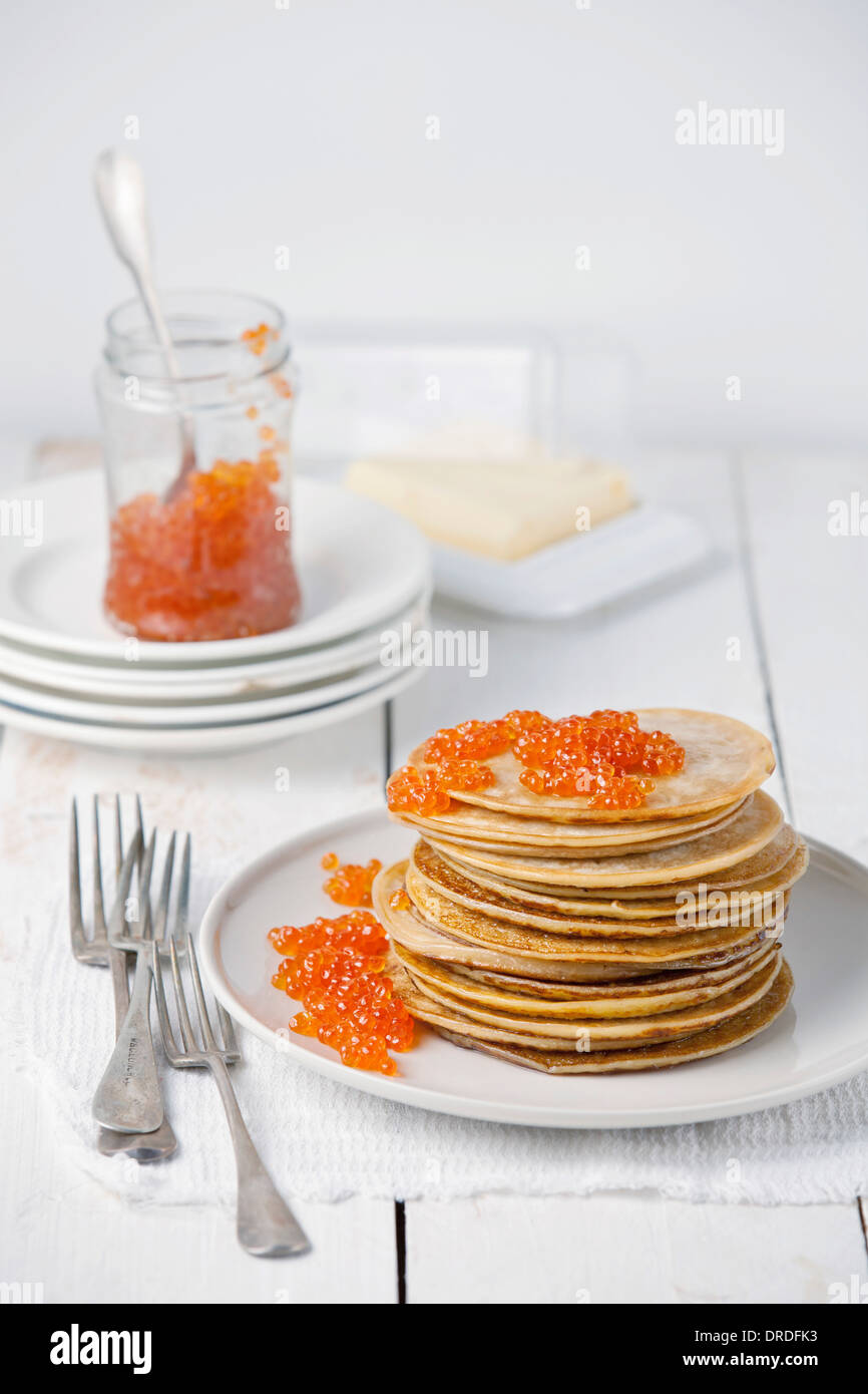 Des crêpes avec du caviar rouge sur fond de bois blanc Banque D'Images