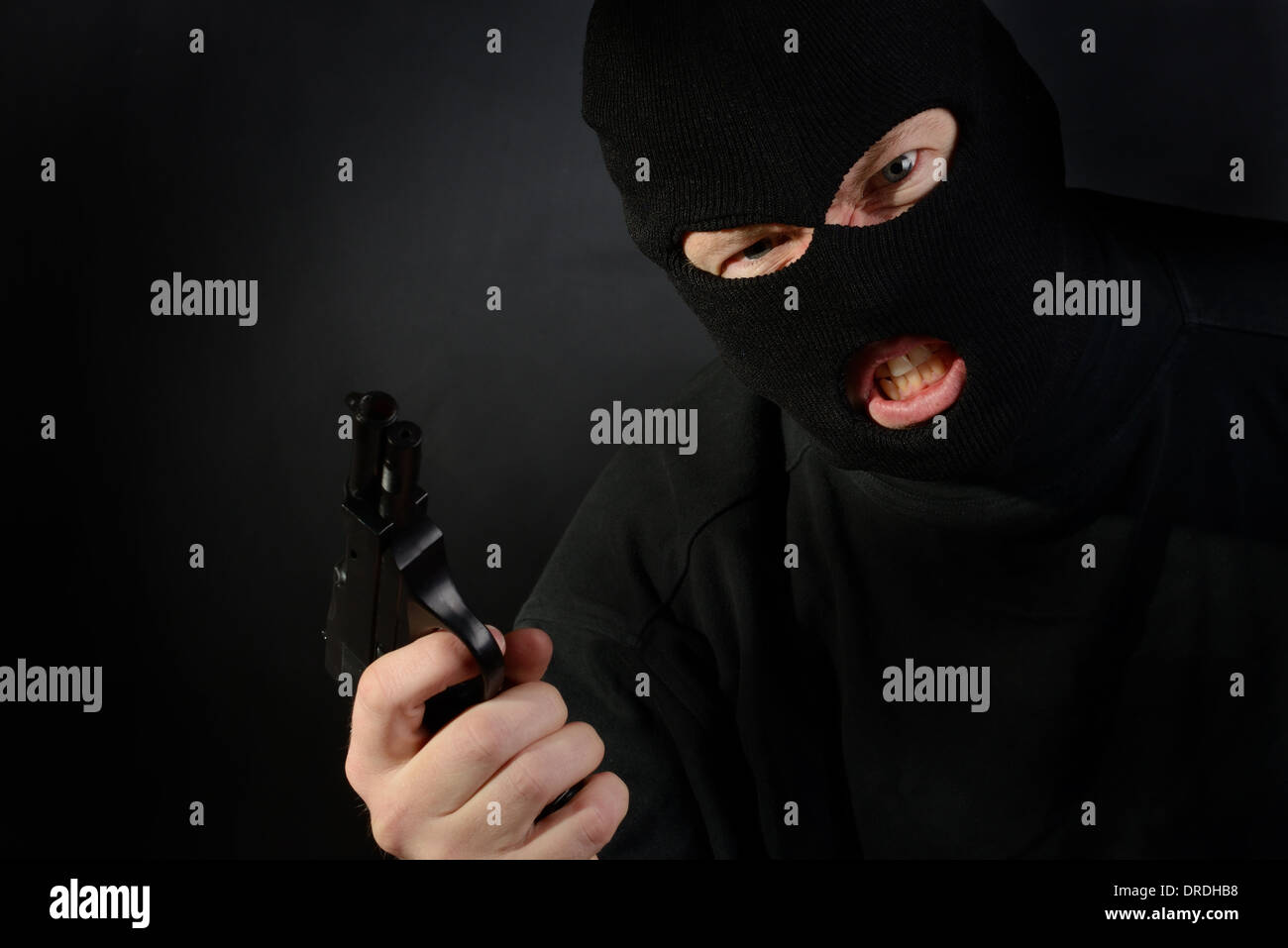 Un masque de ski de terroristes tenant un pistolet avec un fond sombre Banque D'Images