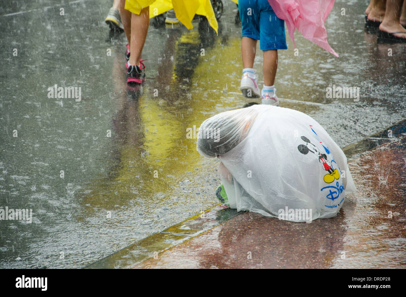 Déçu d'un enfant enveloppé dans un poncho avec le Magic Kingdom Parade était annulé pour cause de pluie à Walt Disney World, Orlando Banque D'Images