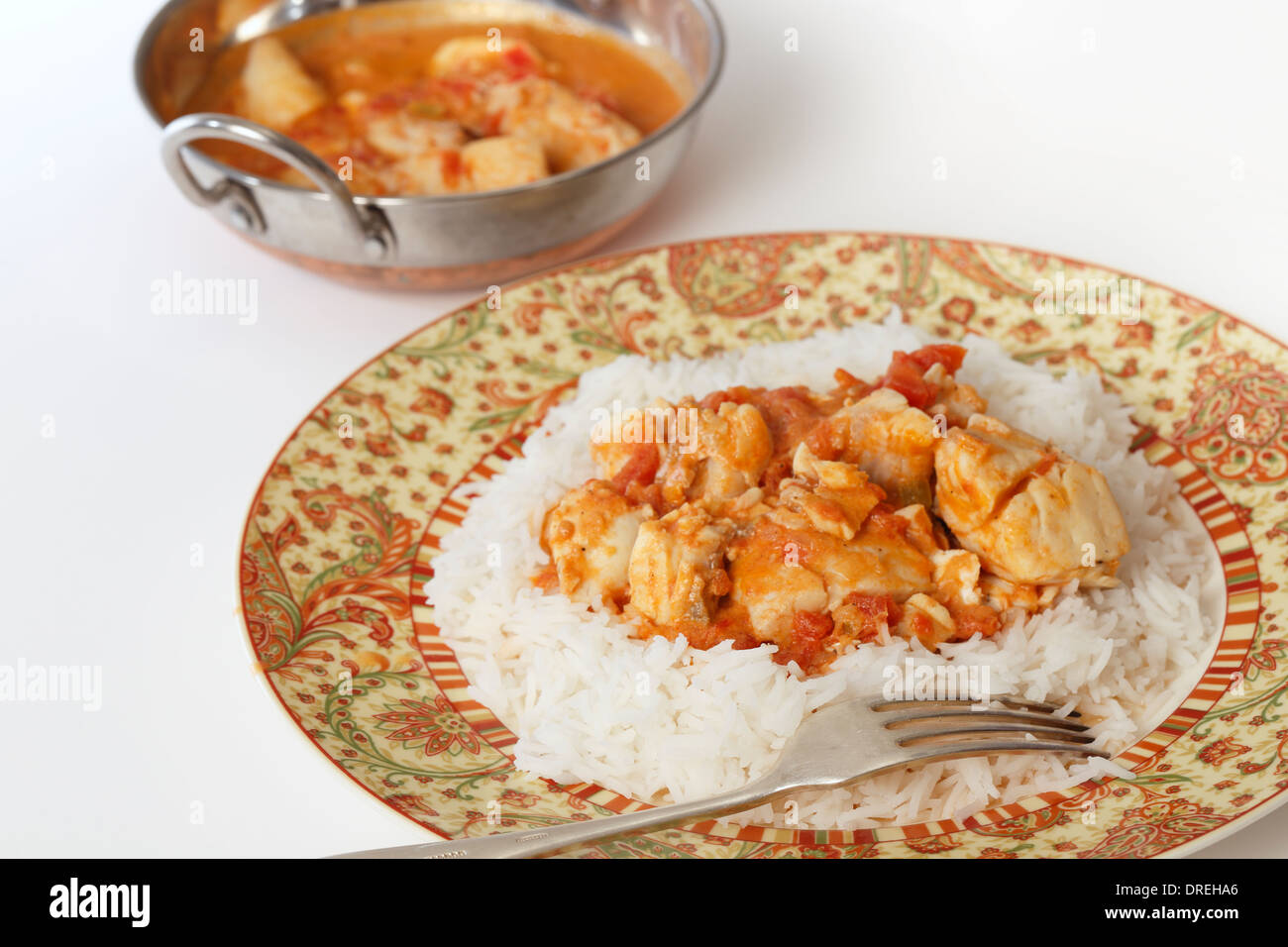 Curry de poisson de base, dans une sauce tomate et sauce au lait de coco, sur un lit de riz basmati, avec un kadai (karahi ou wok) plat de service Banque D'Images