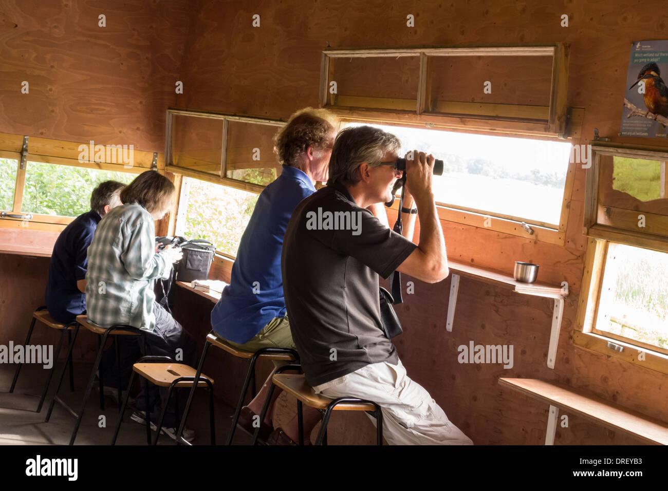Les gens regarder les oiseaux avec les jumelles de se cacher dans un centre de Slimbridge Wetland WWT, Gloucestershire, Royaume-Uni Banque D'Images