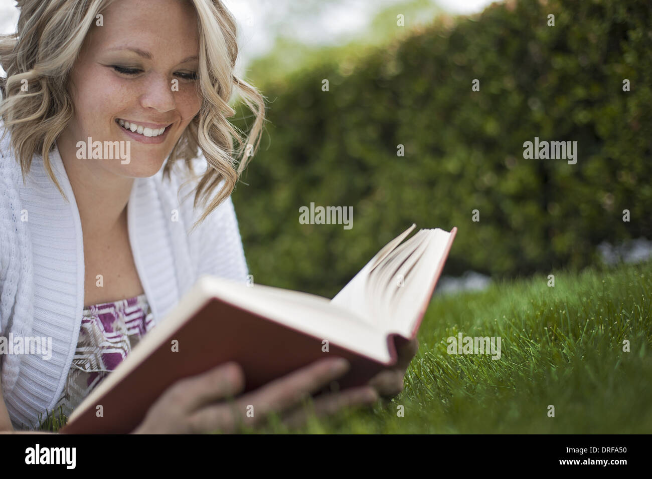 Utah USA girl sitting on the grass in garden reading book Banque D'Images