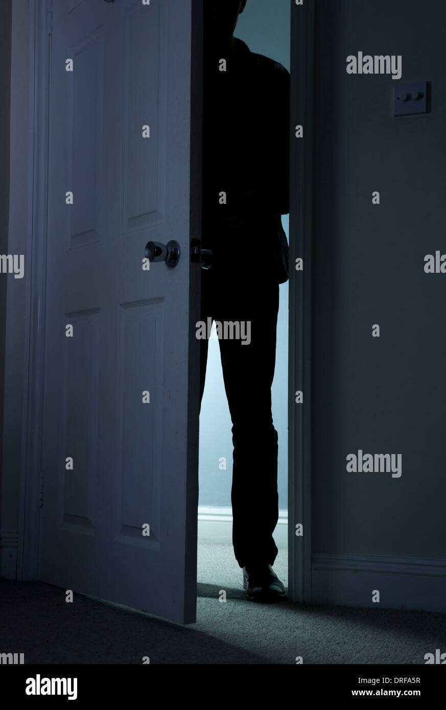 Silhouette d'un homme debout dans le noir, dans une porte ouverte. Banque D'Images