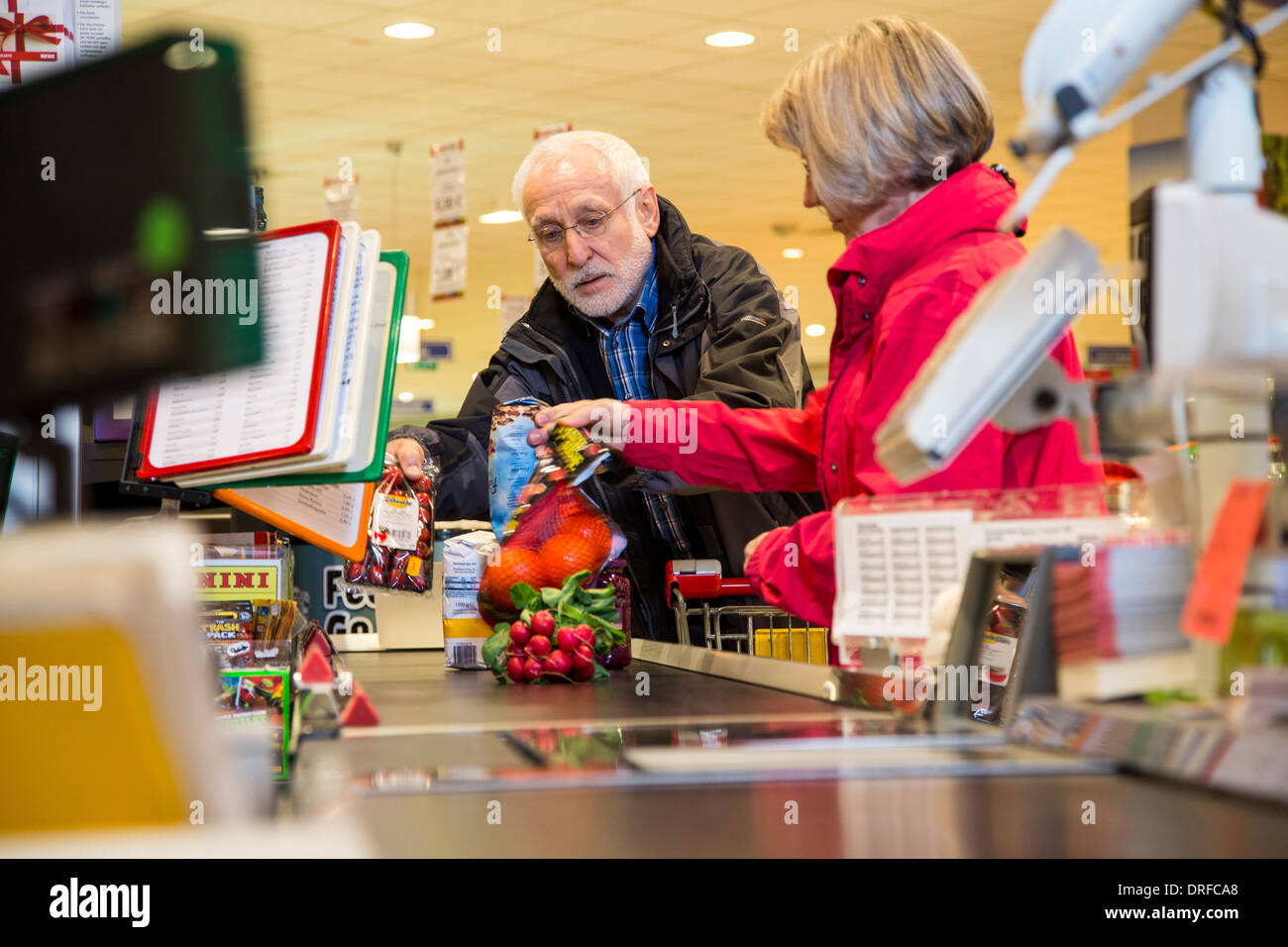 Vieux couple achète dans un supermarché, le caissier, à la caisse. Banque D'Images